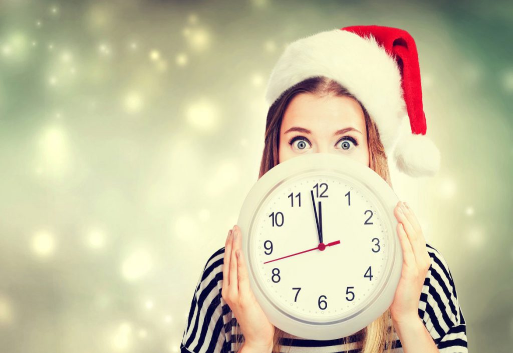 Woman in santa hat holding clock