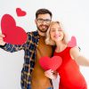 Couple holding paper hearts and smiling